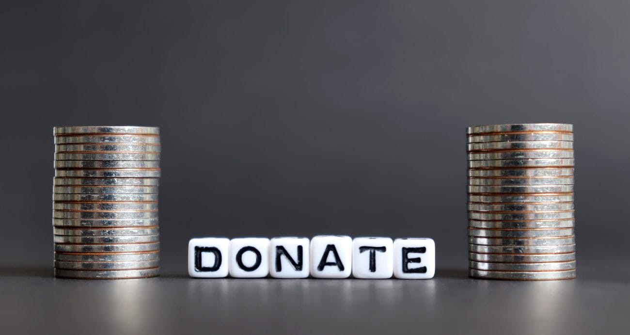 Stacks of coins flank the word DONATE formed by letter blocks, signaling fundraising or contribution appeal.&nbsp;Hispamer Noticias