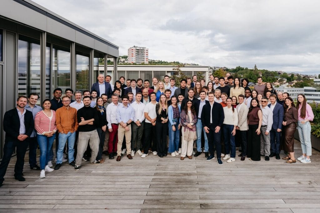 Group of diverse professionals posing on a rooftop deck with a city skyline in the background, overcast sky above.&nbsp;Hispamer Noticias