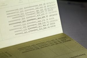 Close-up of a bank statement page filled with rows of numeric figures and asterisks, like a financial ledger above a darker surface.&nbsp;Hispamer Noticias