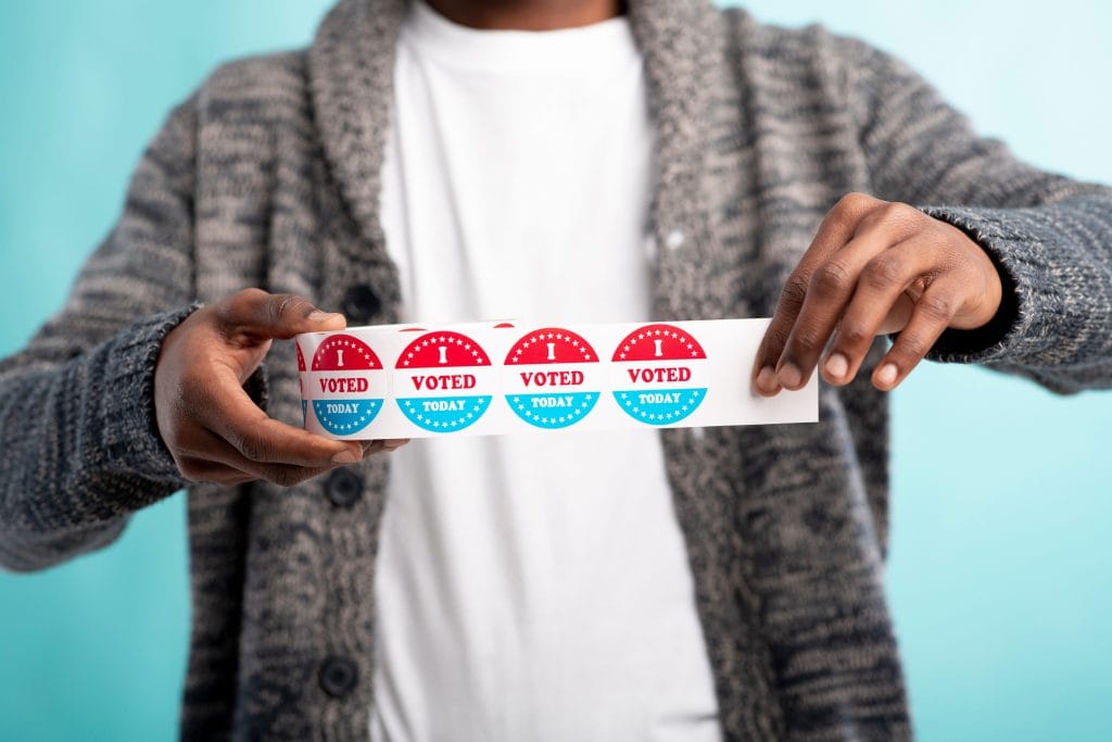 Person holds a strip of red-and-blue 'I Voted Today' stickers stretched between their hands.&nbsp;Hispamer Noticias