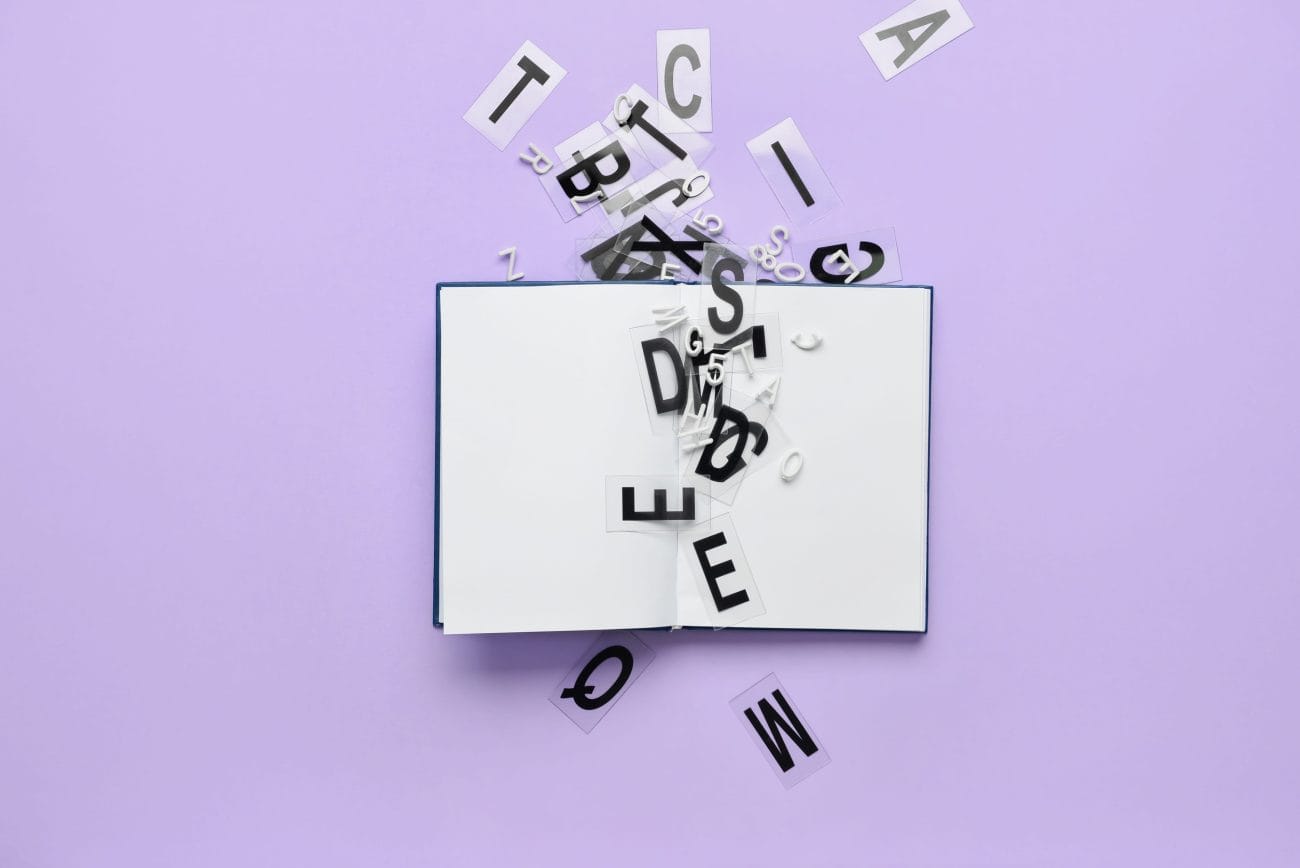 Blank book with letters on color background - Hispamer Noticias Open book with black letters spilling out onto a purple background, like words escaping from the pages. Hispamer Noticias