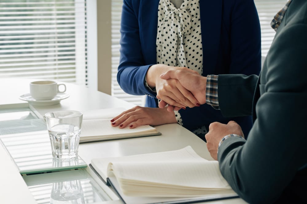 Two professionals shake hands over a desk with notebooks, signaling an agreement in a meeting setting&nbsp;Hispamer Noticias