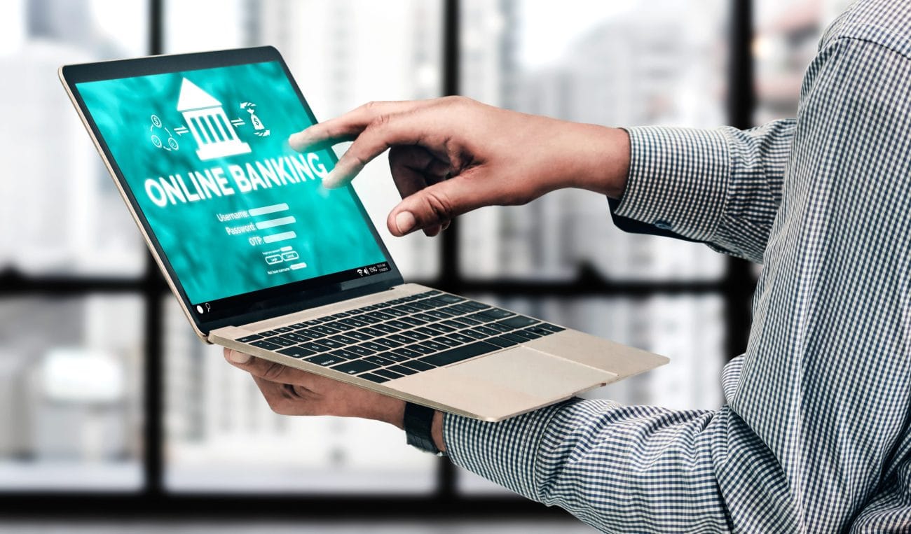 embargos online - Hispamer Noticias Person holds a laptop showing an online banking login screen with 'ONLINE BANKING' text on a teal background. Hispamer Noticias