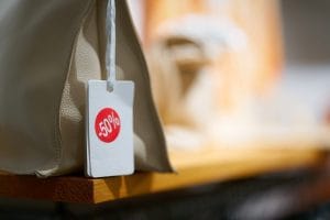 Beige handbag on a wooden shelf with a white sale tag showing -50% discount.&nbsp;Hispamer Noticias