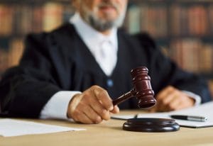 Judge in a black robe raises a wooden gavel over a desk during a courtroom proceeding.&nbsp;Hispamer Noticias