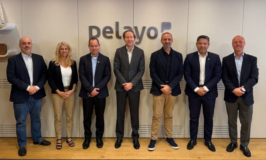 Seven professionals in business attire standing in a row in an office lobby, with a company logo on the wall behind them.&nbsp;Hispamer Noticias