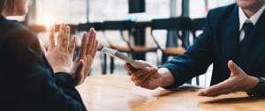 corrupcion españa - Hispamer Noticias Two people in business attire exchange a stack of bills across a wooden table, one handing money to the other while gesturing with the free hand. Hispamer Noticias
