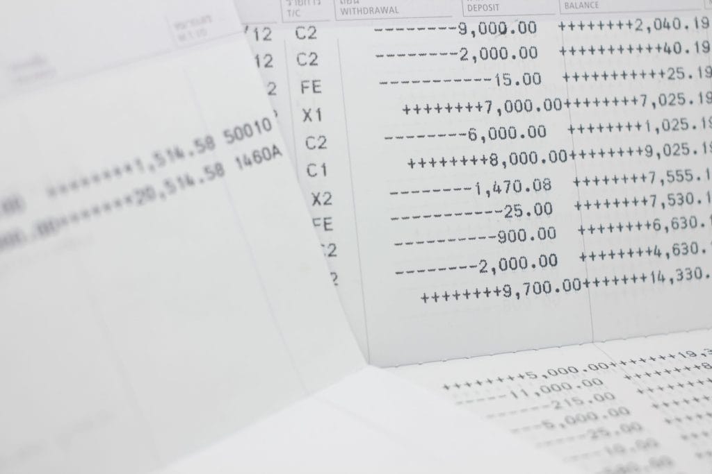Close-up of financial documents with columned numbers and symbols (ledger/statement pages) scattering across a desk to convey banking data.&nbsp;Hispamer Noticias