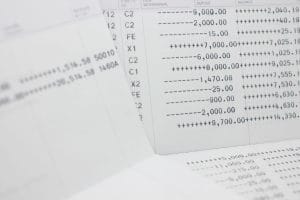 Close-up of financial documents with columned numbers and symbols (ledger/statement pages) scattering across a desk to convey banking data.&nbsp;Hispamer Noticias