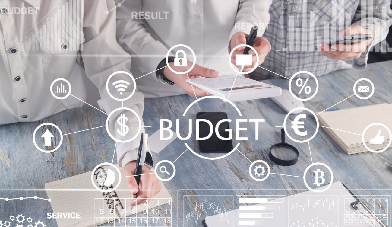 People working at office Concept of Budget business Finance - Hispamer Noticias Illustration of budgeting concept with interconnected icons (currency, charts, lock, percentage) and the word BUDGET at center on a desk scene. Hispamer Noticias