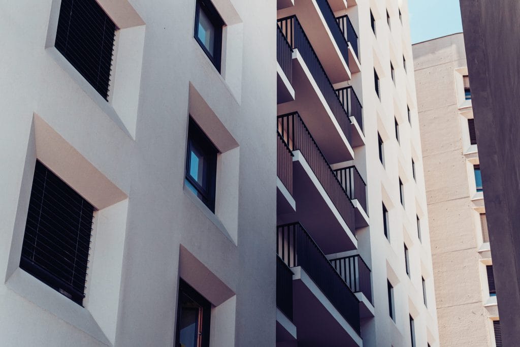 White apartment building with multiple protruding windows and dark balcony rails along the right, blue sky visible above.&nbsp;Hispamer Noticias