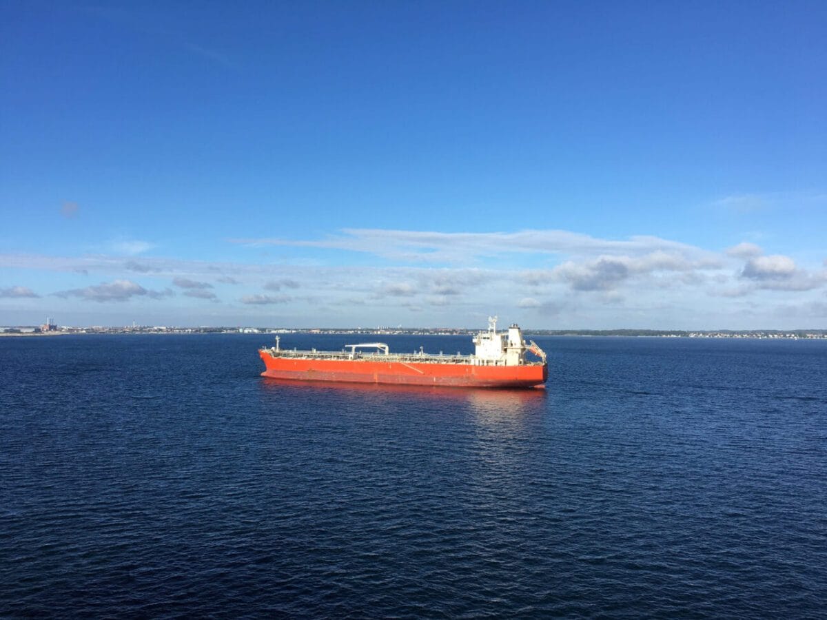Oil tanker outside Copenhagen Denmark - Hispamer Noticias A large red cargo ship sails on calm blue water with a distant shoreline on the horizon under a clear sky. Hispamer Noticias