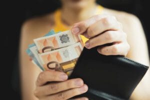 finanzas 2026 - Hispamer Noticias Person holding a black wallet with several euro banknotes protruding from it, ready to spend or count money on display. Hispamer Noticias