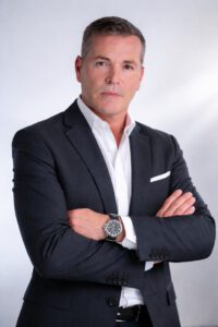 Professional headshot of a man in a dark suit with arms crossed, white shirt, and a wristwatch.&nbsp;Hispamer Noticias