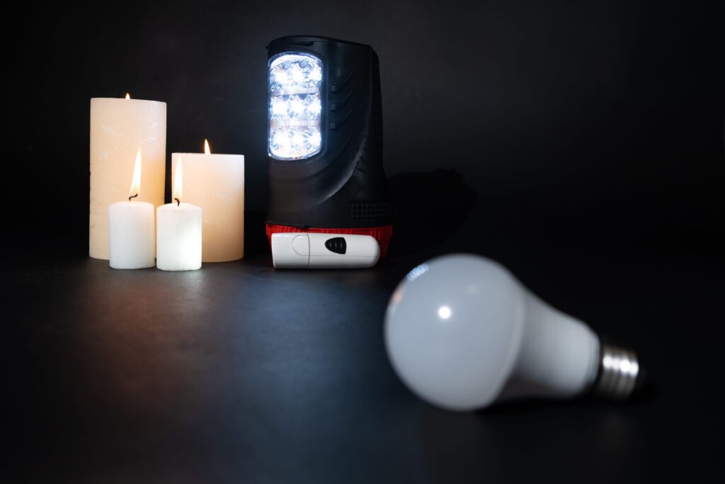 Candles and a portable LED work light on a dark surface, with a loose LED bulb in the foreground.&nbsp;Hispamer Noticias