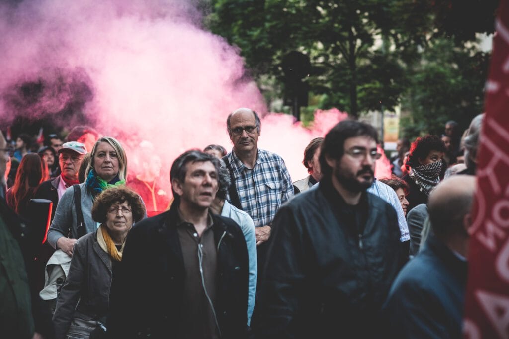 Group of protesters walking through a street as pink smoke billows in the background.&nbsp;Hispamer Noticias