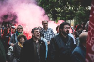 huelga general - Hispamer Noticias Group of protesters walking through a street as pink smoke billows in the background. Hispamer Noticias