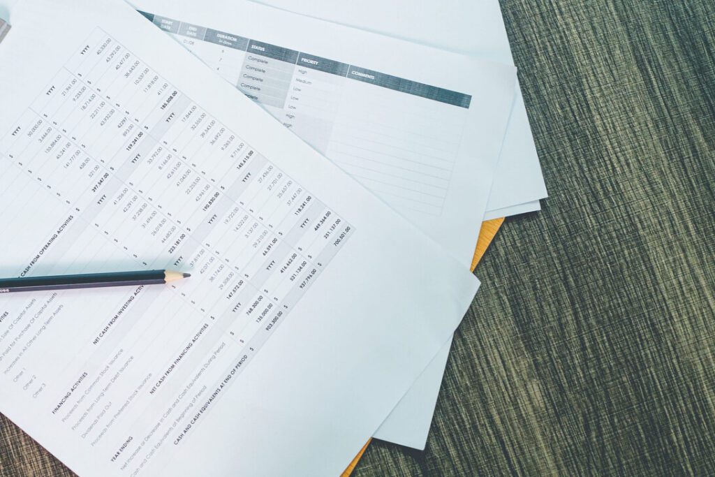 Spreadsheets and financial reports spread on a wooden desk, with a pencil resting on one page.&nbsp;Hispamer Noticias