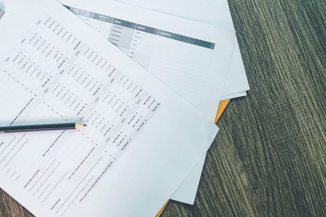 Spreadsheets and financial reports spread on a wooden desk, with a pencil resting on one page.&nbsp;Hispamer Noticias